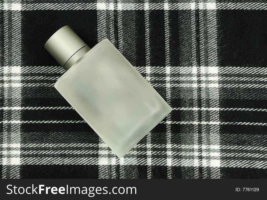 Bottle of cologne on hight contrast black and white checkered pattern with plenty of copyspace for advertising text. Bottle of cologne on hight contrast black and white checkered pattern with plenty of copyspace for advertising text