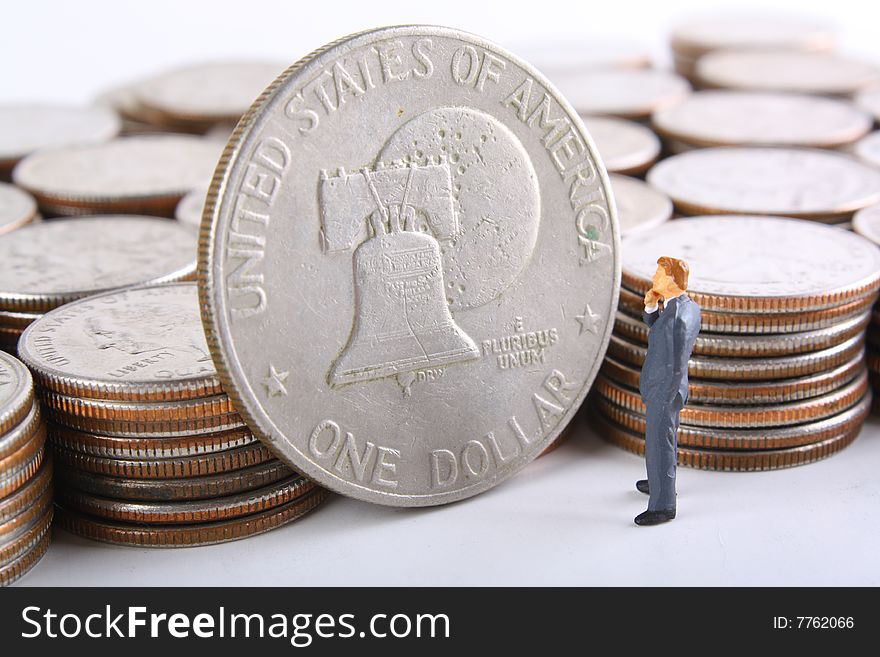 Miniature businessman looking at silver dollar.