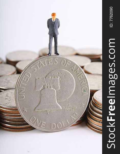 Miniature businessman looking at silver dollar.
