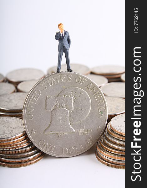 Miniature businessman standing on silver dollar.