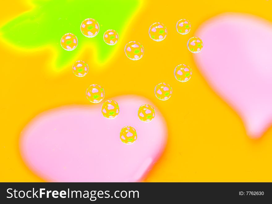 Water drops in the form of heart on a multi-coloured celebratory background