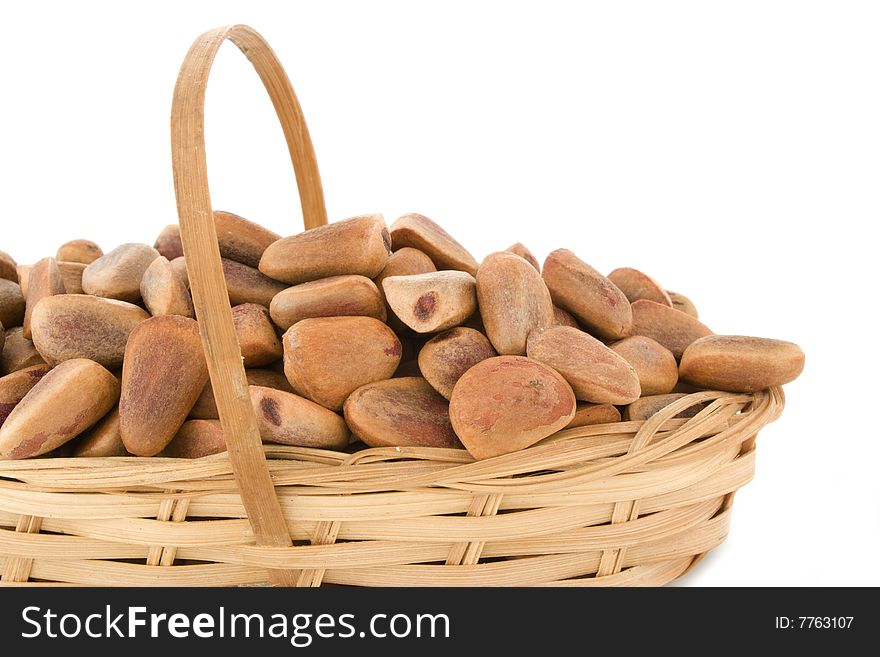 The crude pine nuts in a basket on a white background