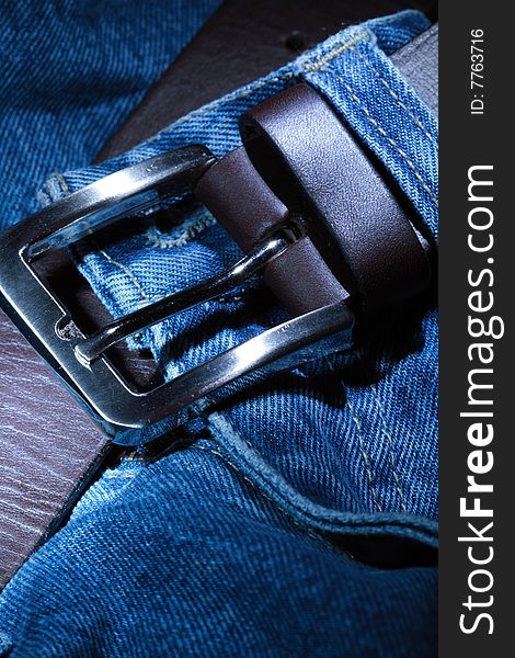 Close-up of  leather belt with steel buckle lying on jeans. Close-up of  leather belt with steel buckle lying on jeans