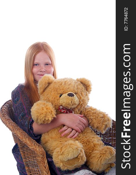 Redhead girl and her big toy bear are sitting in the armchair