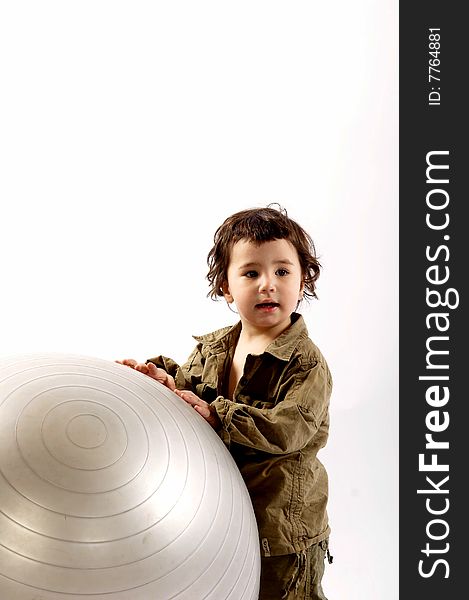 Little boy plays with a big silver ball in photo studio