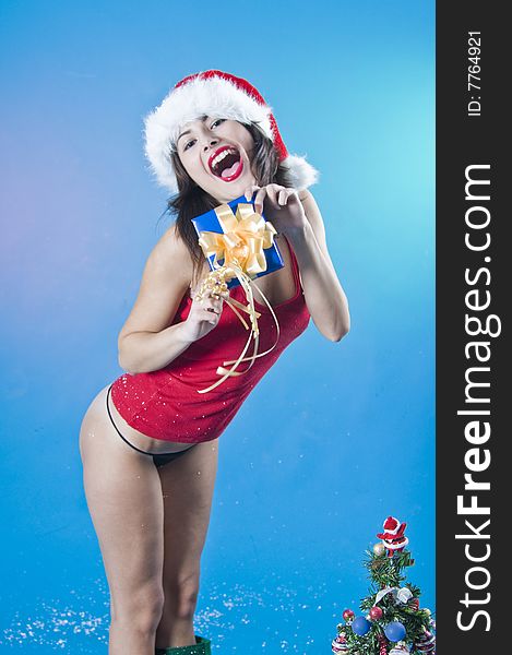 A sexy teenage model holding a present while posing near a Christmas tree. A sexy teenage model holding a present while posing near a Christmas tree