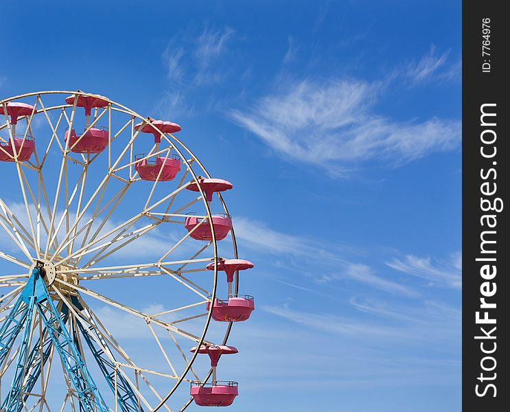 Ferris wheel against a blue sky with space for text