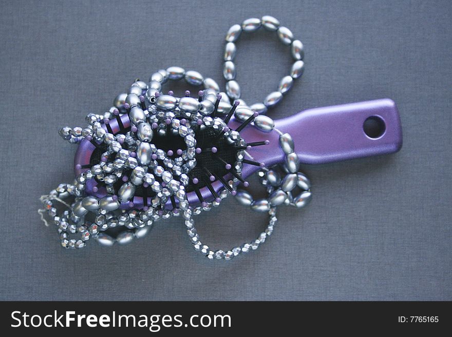 Hairbrush and necklace entwined lying on a table top