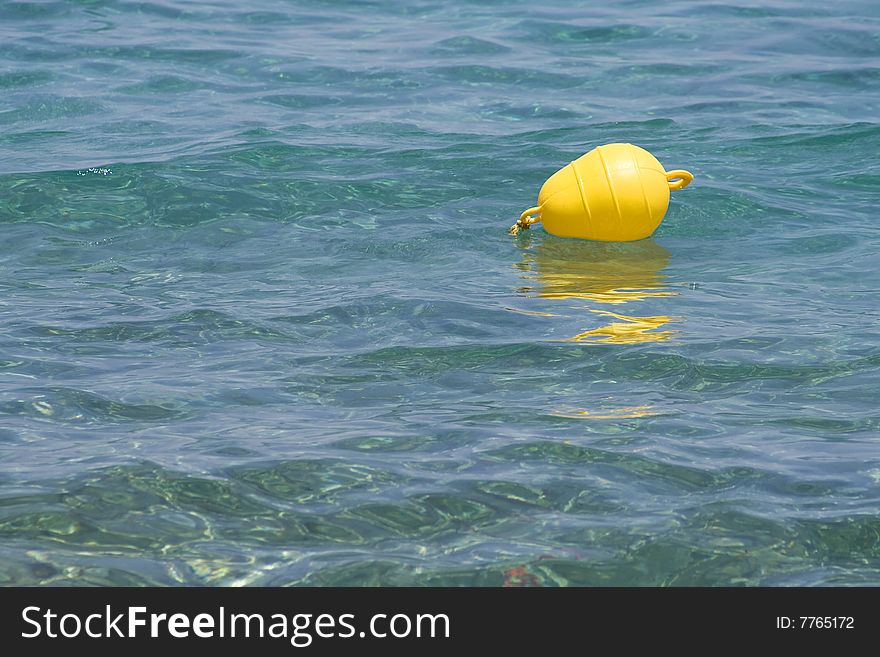 Brightly-coloured float designates area for boats on blue sea. Brightly-coloured float designates area for boats on blue sea