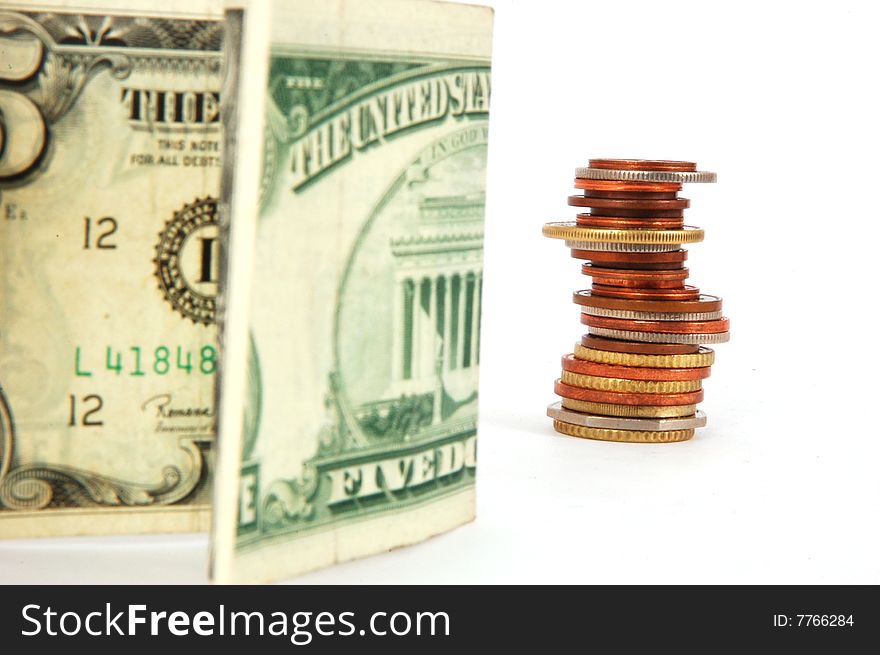 Five dollar paper money and column of coins isolated on the white background.