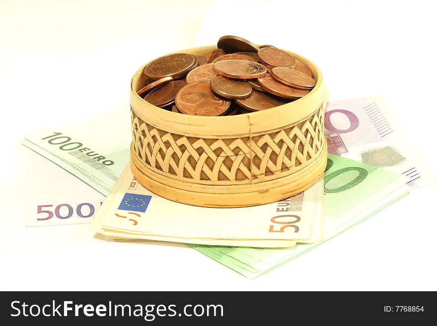 Carved wooden box full of coins on banknotes of euro, isolated on a white