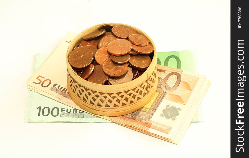 Carved wooden box full of coins on banknotes of euro, isolated on a white