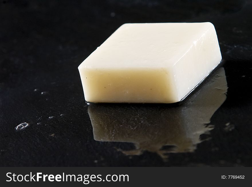 Bar of white soap on wet black slate