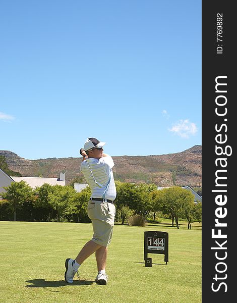 Young male golfer hitting the ball from the fairway on a beautiful summer day. Young male golfer hitting the ball from the fairway on a beautiful summer day