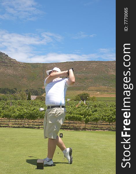 Young male golfer hitting the ball from the fairway on a beautiful summer day. Young male golfer hitting the ball from the fairway on a beautiful summer day