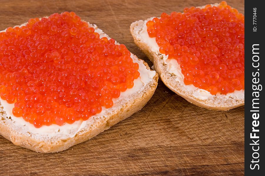 Sandwiches with red caviar on an oak board