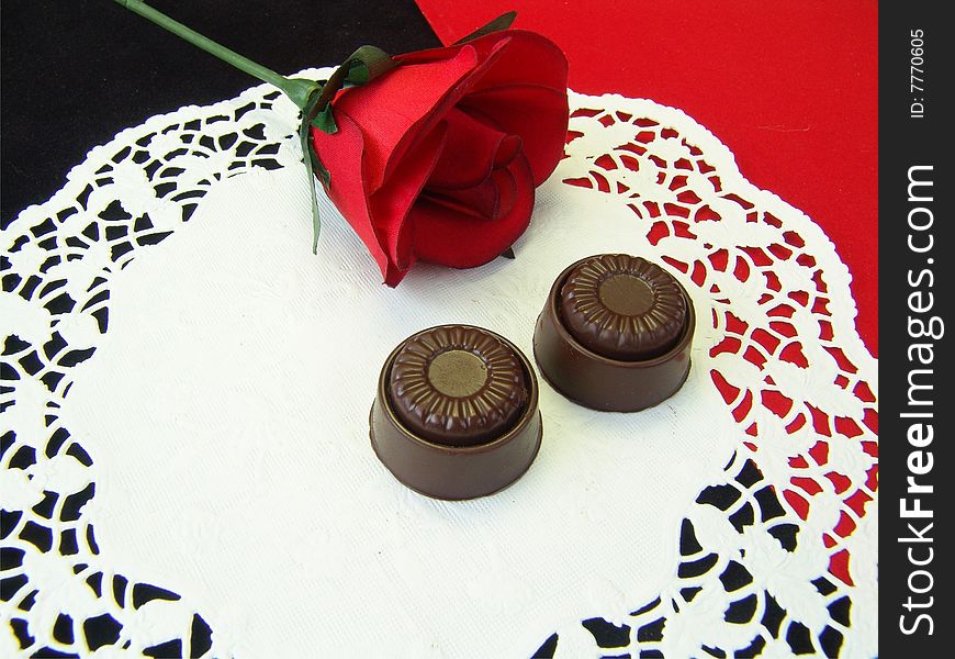 Chocolates and rose on a white dolley with red and black background giving an expressing of love