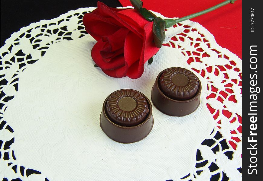 Chocolates and rose on a white dolley with red and black background giving an expressing of love