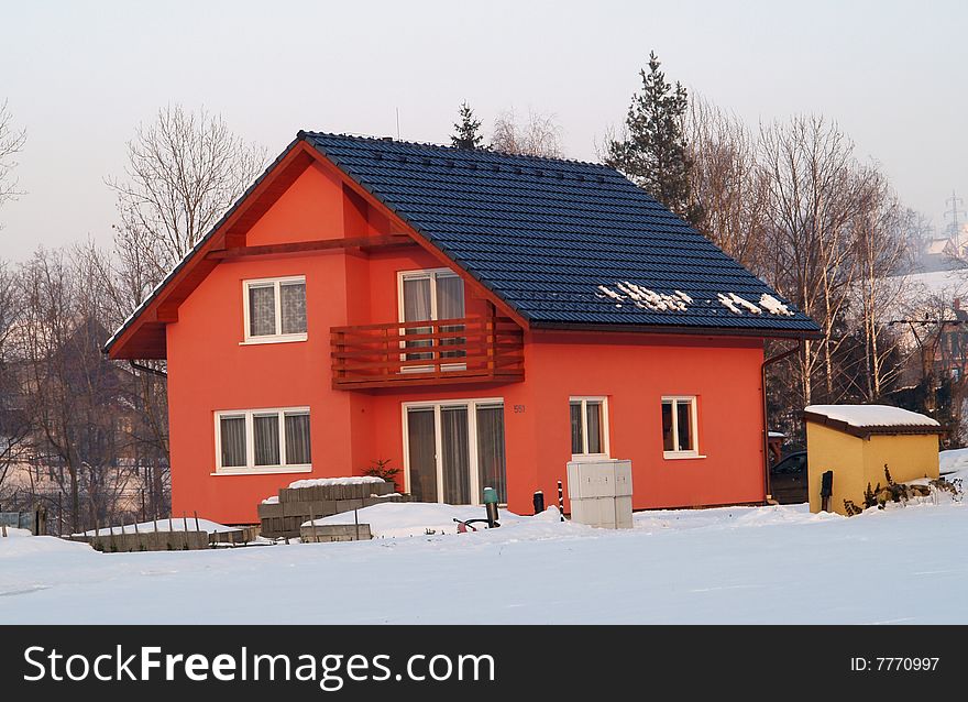 Red colored house with black roof in winter. Red colored house with black roof in winter