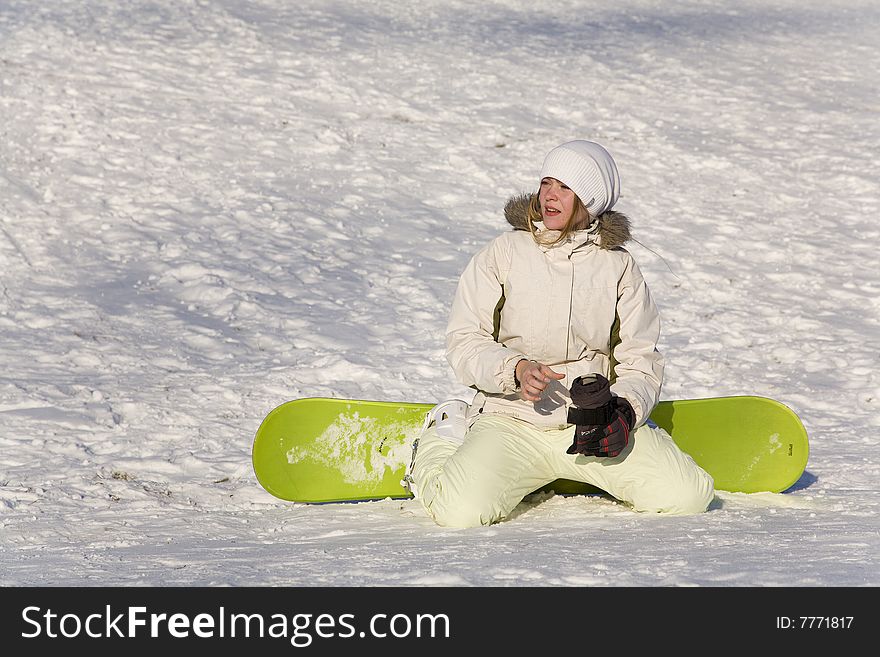 Woman with snowboard sitting on snow