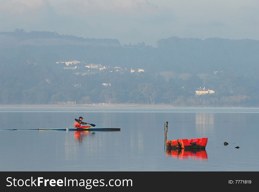 Sillouette of man kayaking on Óbidos Lagoon with mist