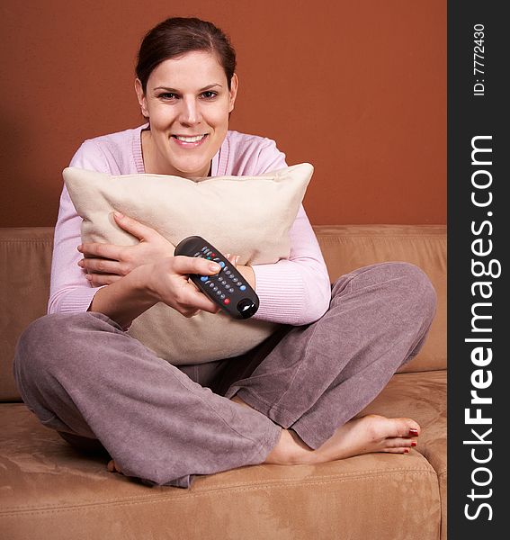 A young woman sits in front of a TV with the remote control in her hand on a couch. A young woman sits in front of a TV with the remote control in her hand on a couch.
