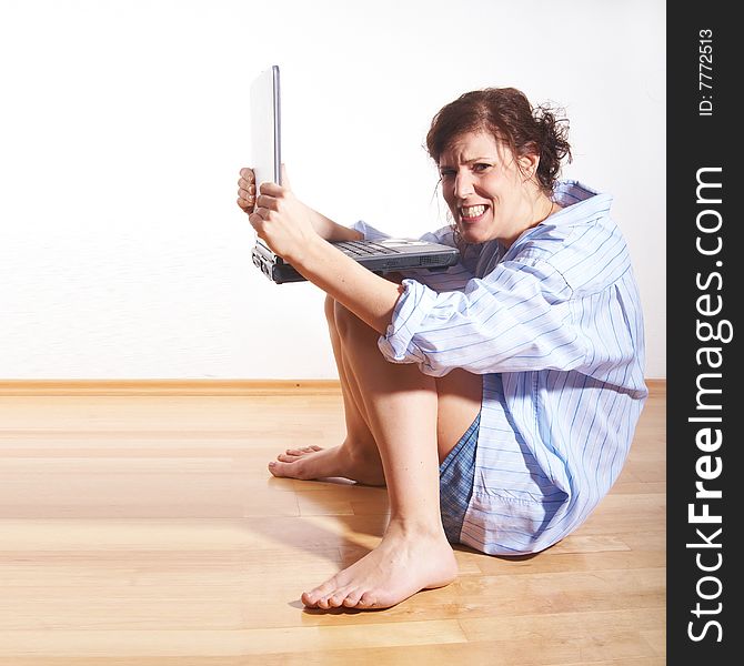 A young woman at home with her laptop sitting on the floor in her new appartment. She seems to be very frustrated. A young woman at home with her laptop sitting on the floor in her new appartment. She seems to be very frustrated.