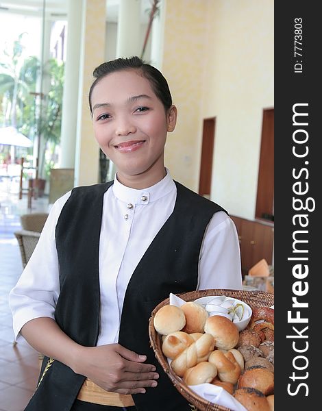 Waitress at work holding bread basket smiling