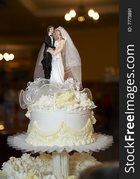 Figurine of a groom and a bride decorated higher part of the wedding cake. Figurine of a groom and a bride decorated higher part of the wedding cake.