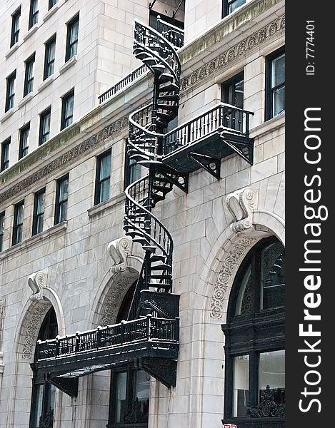 Ornate wrought iron spiral fire escape on the front of a highly decorated building in the snow