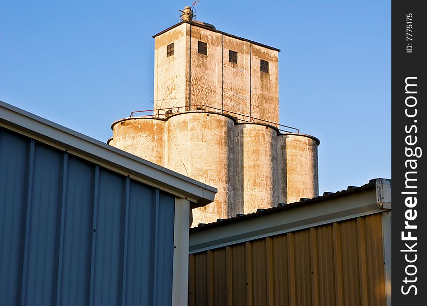 Grain silo behind two colorful buildings