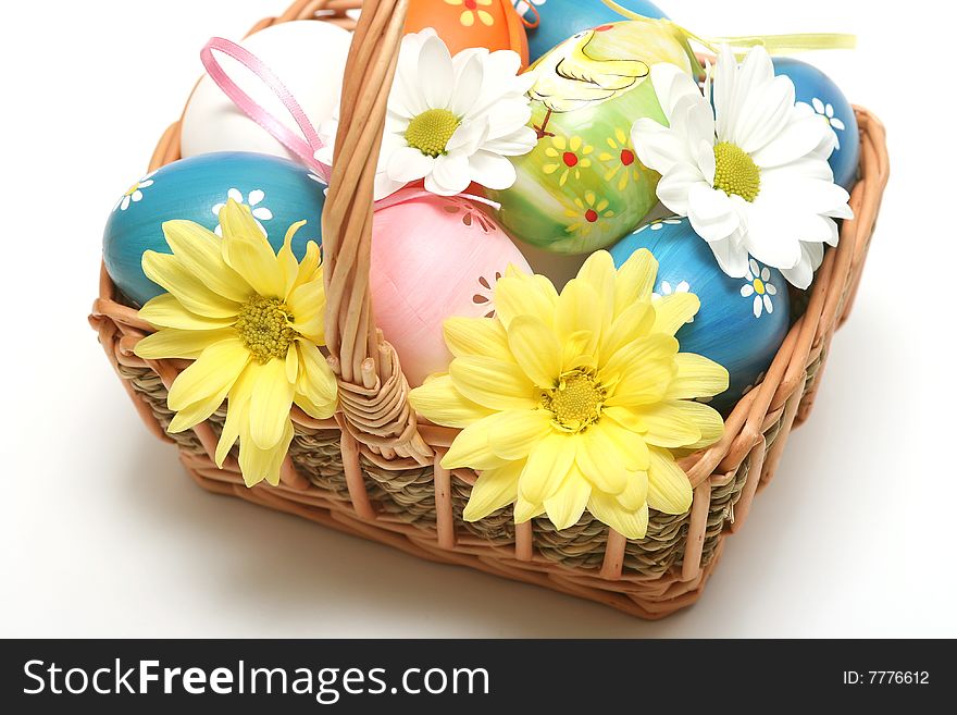 Easter basket with easter eggs and flower on vhite background.