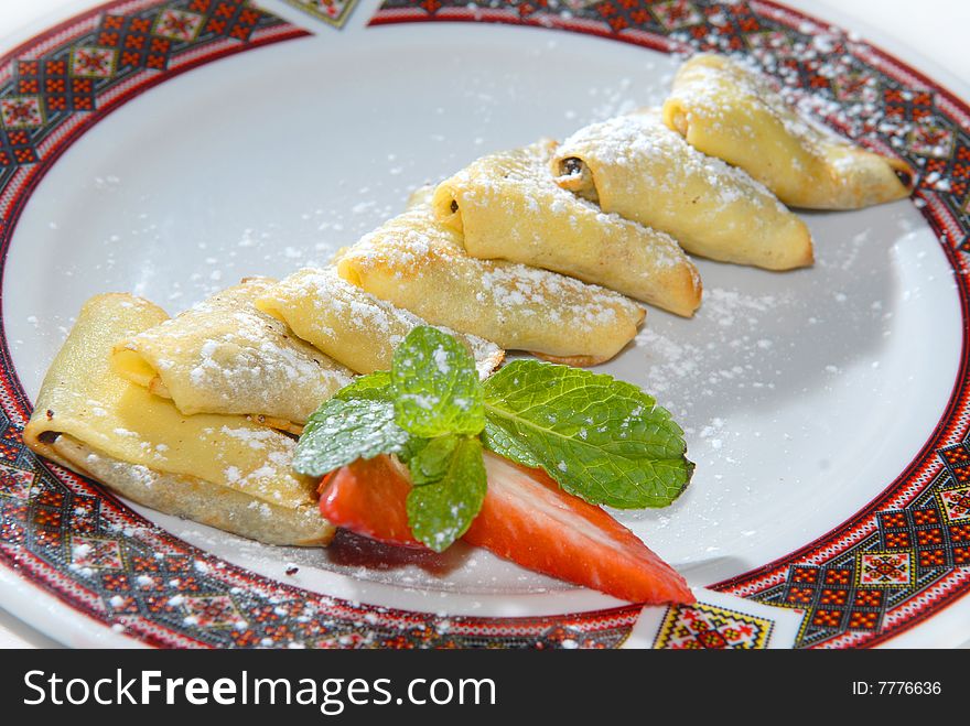 Pancakes with raisin and prunes on a plate with the Ukrainian ornament