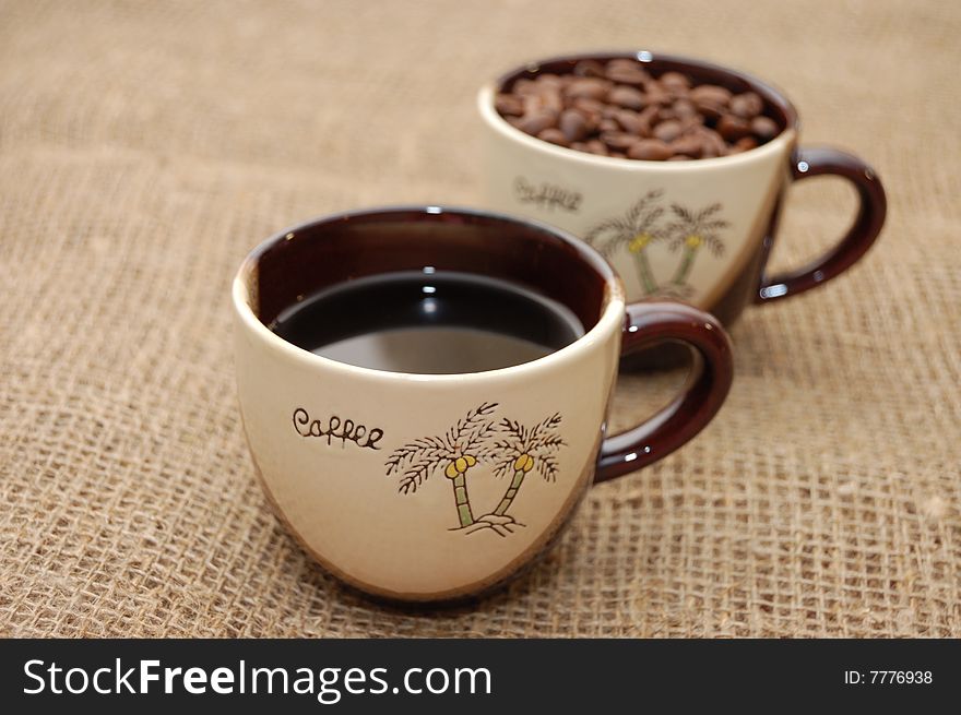 Two coffee cups: one with beverage and other with beans