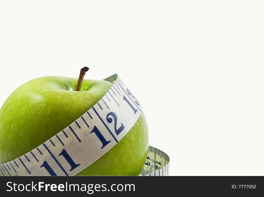 A closeup shot of a single green apple wrapped by a a measuring tape with the apple placed on the lower left with enough room for copyspace. A closeup shot of a single green apple wrapped by a a measuring tape with the apple placed on the lower left with enough room for copyspace