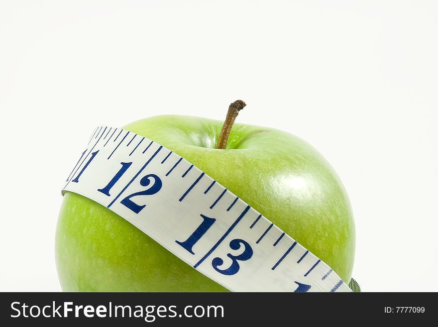 a juicy green apple wrapped by a measuring tape isolated on white.  shot up close and intentionally off centered.