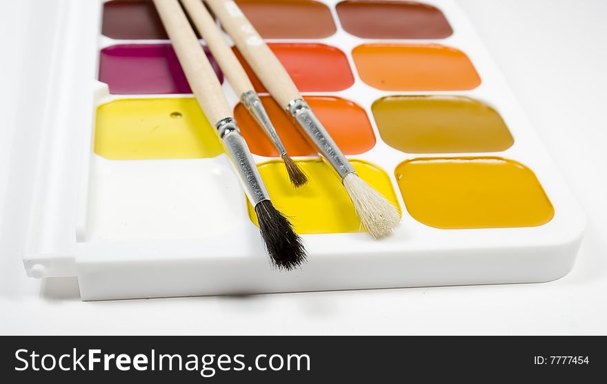 Set of water colour paints with paintbrushs on white