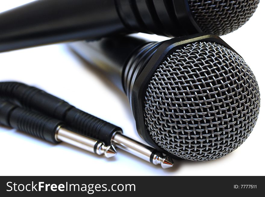 Two black wired karaoke microphones with gray metal grill on isolated background. Two black wired karaoke microphones with gray metal grill on isolated background.