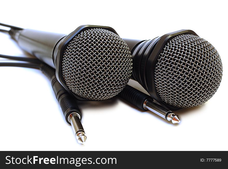 Two black wired karaoke microphones with gray metal grill on isolated background. Two black wired karaoke microphones with gray metal grill on isolated background.