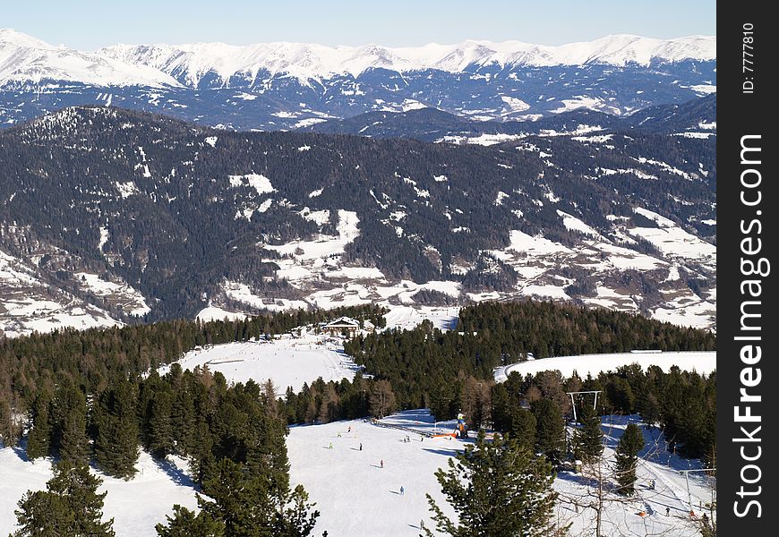 Snowy Mountains with trees and skiers