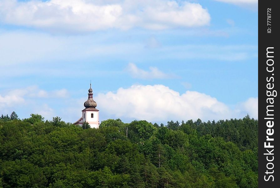 Church tower jutting out of the forest.