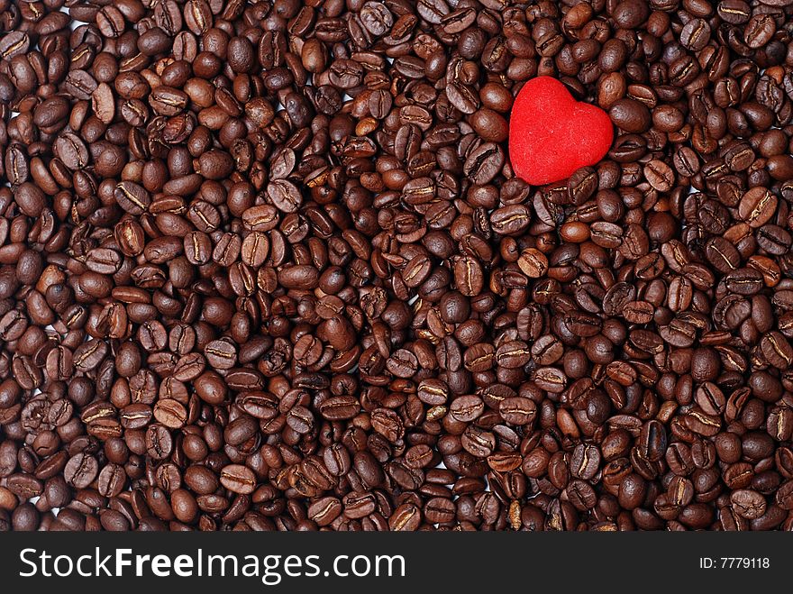 Red heart in the heap of brown coffee beans. Red heart in the heap of brown coffee beans