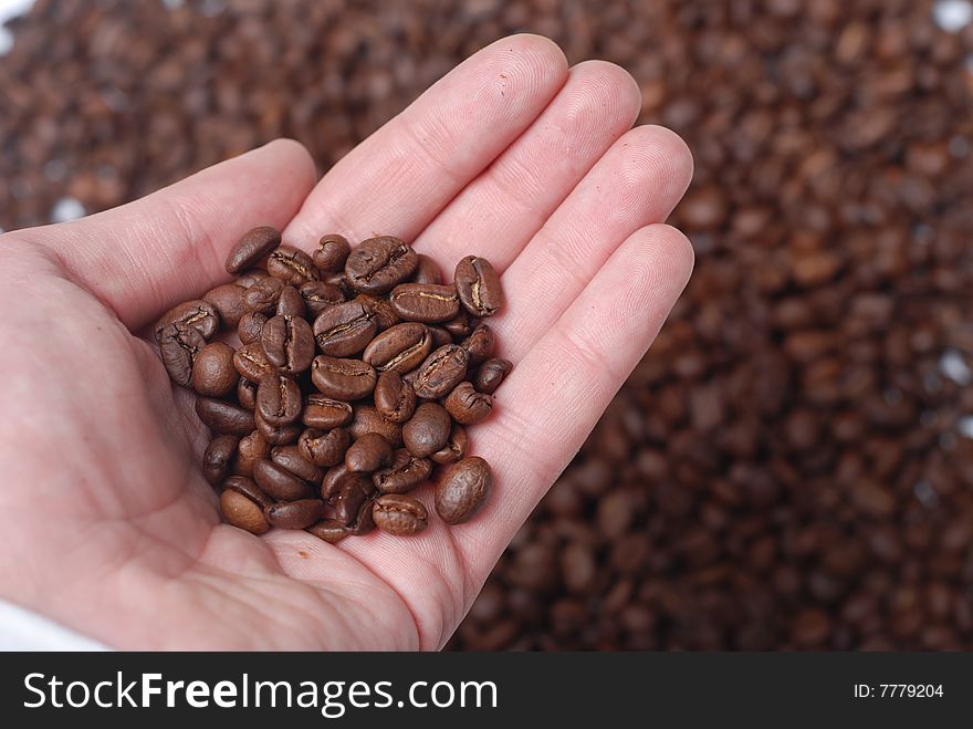 Hand of man with heap of brown coffee beans. Hand of man with heap of brown coffee beans