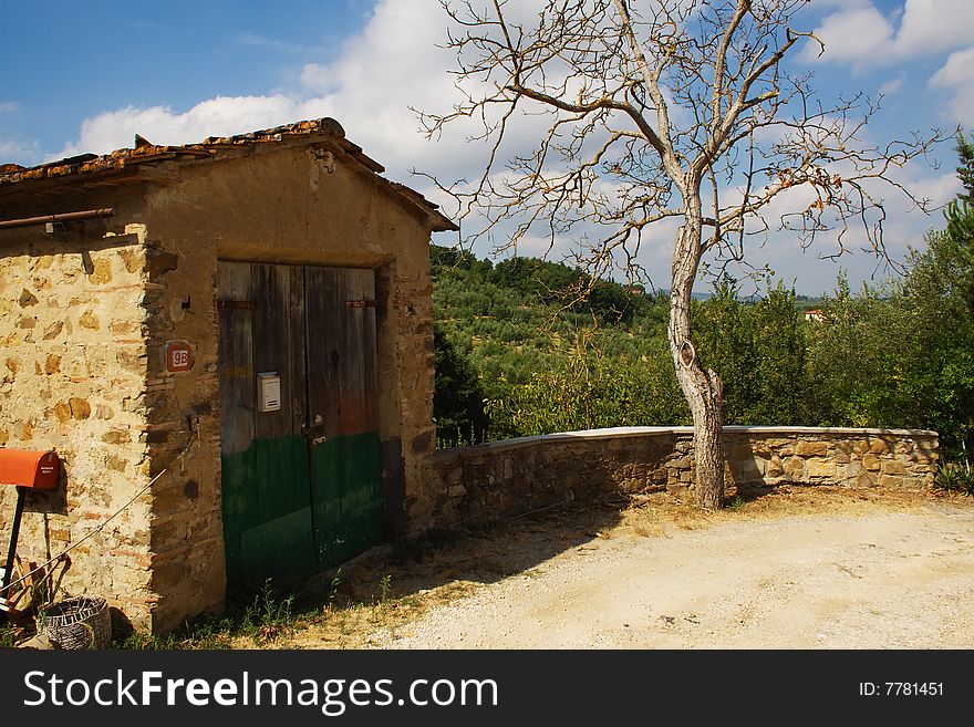 Tuscany country scene with hill on the background, tree and garage on the foreground