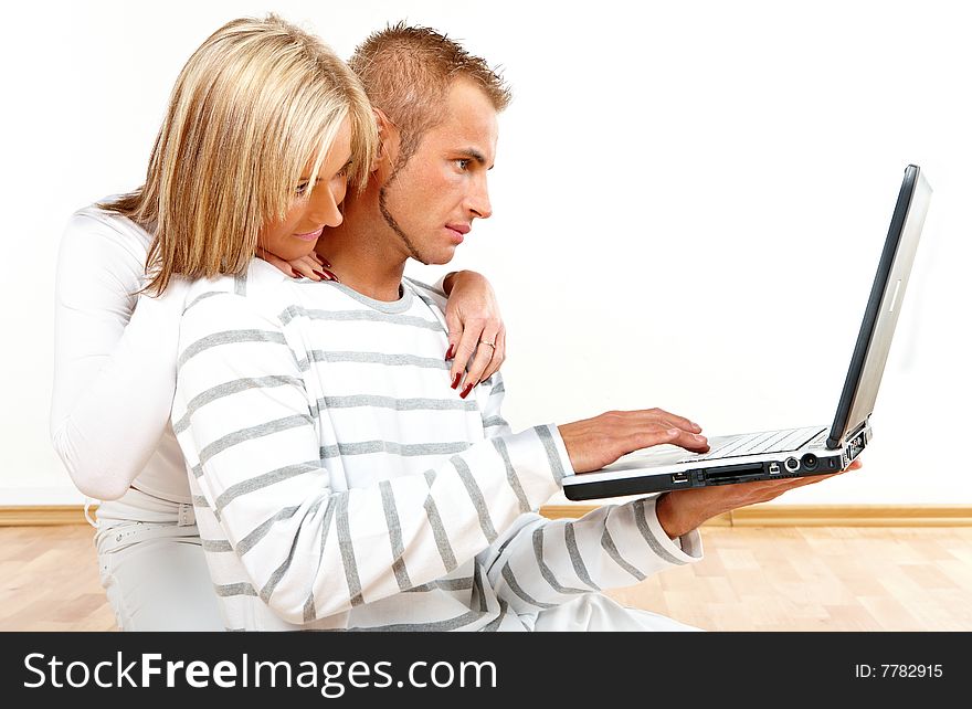 Portrait of a happy couple sitting on the floor with laptop. Portrait of a happy couple sitting on the floor with laptop