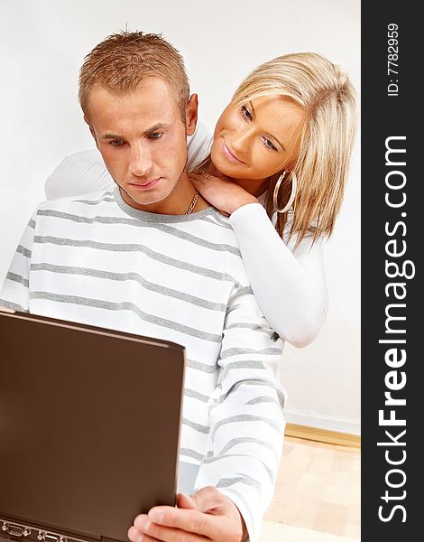 Portrait of a happy couple sitting on the floor with laptop. Portrait of a happy couple sitting on the floor with laptop