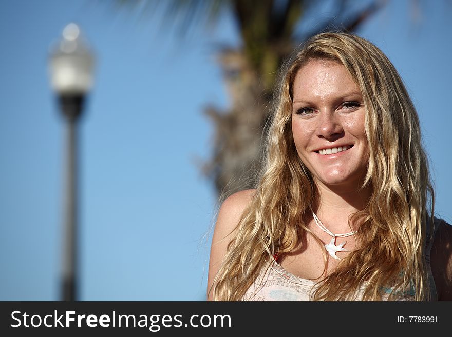 Woman smiling with a lamp post and a tree on the blue background