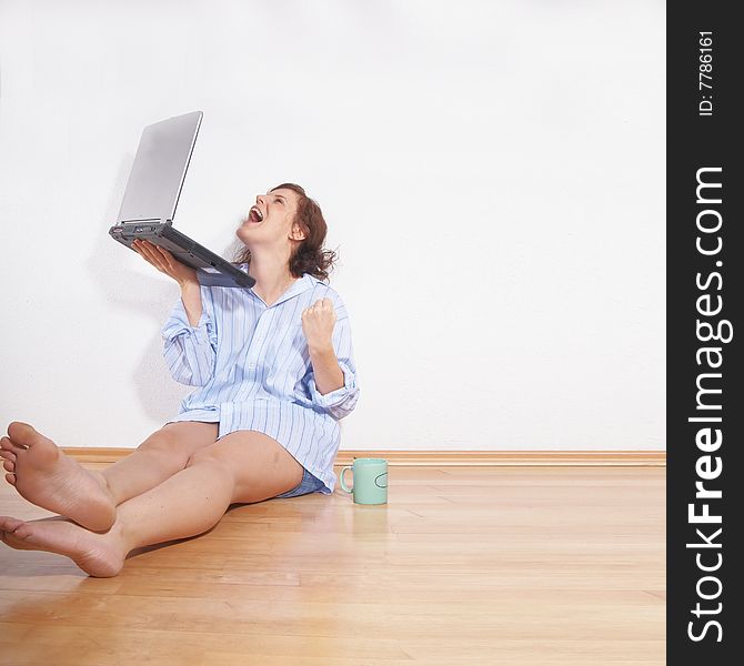 A young woman with a laptop on the floor at home. She is very happy and is celebrating. A young woman with a laptop on the floor at home. She is very happy and is celebrating.