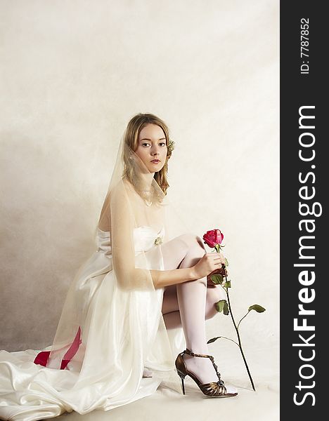 Beautiful bride sits with a red rose