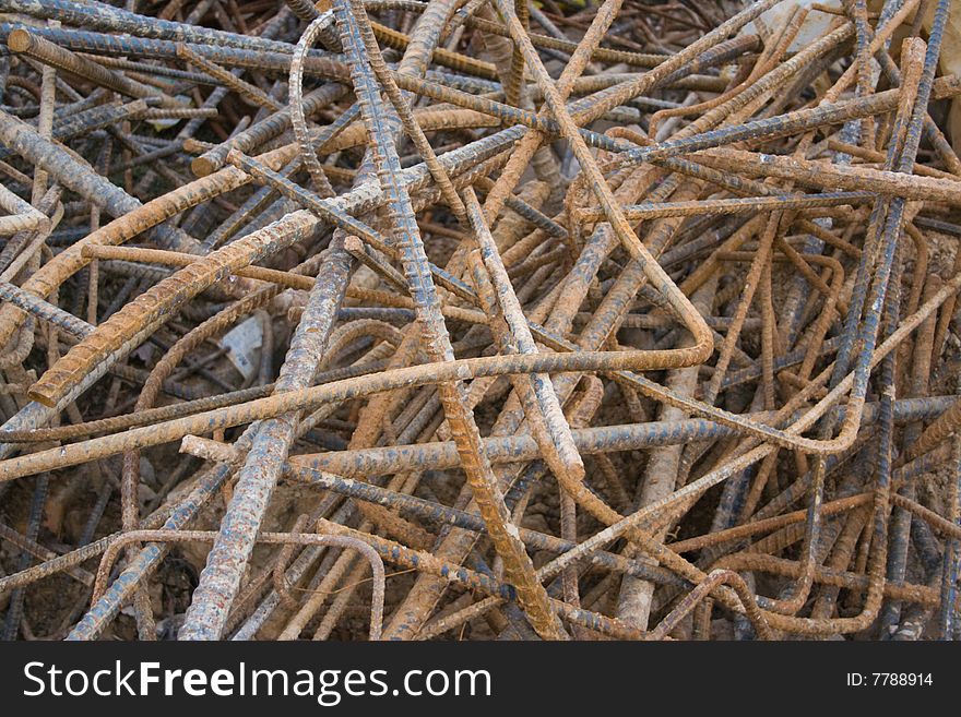 A chaotic pile of bent and rusty scrap rebar (steel reinforcement bar) at a construction site. Useful as a background, with great texture. A chaotic pile of bent and rusty scrap rebar (steel reinforcement bar) at a construction site. Useful as a background, with great texture.